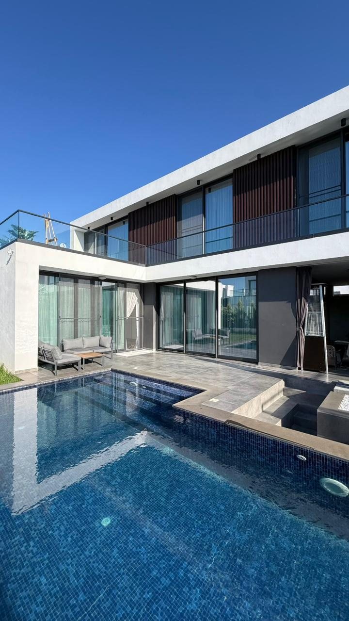 Two-storey villa with glass facade and private pool in daylight