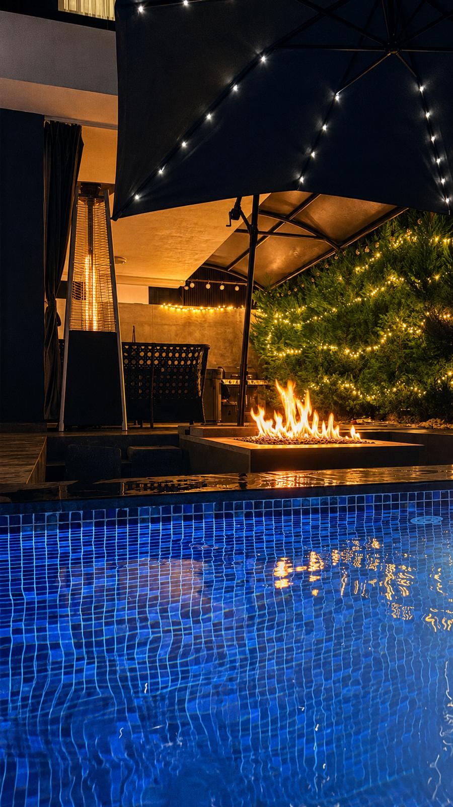 Pool at night with fire table and covered lounge