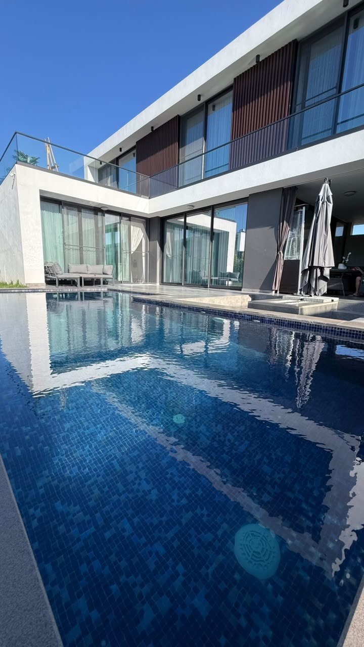 Two-storey villa with glass facade reflected in the pool