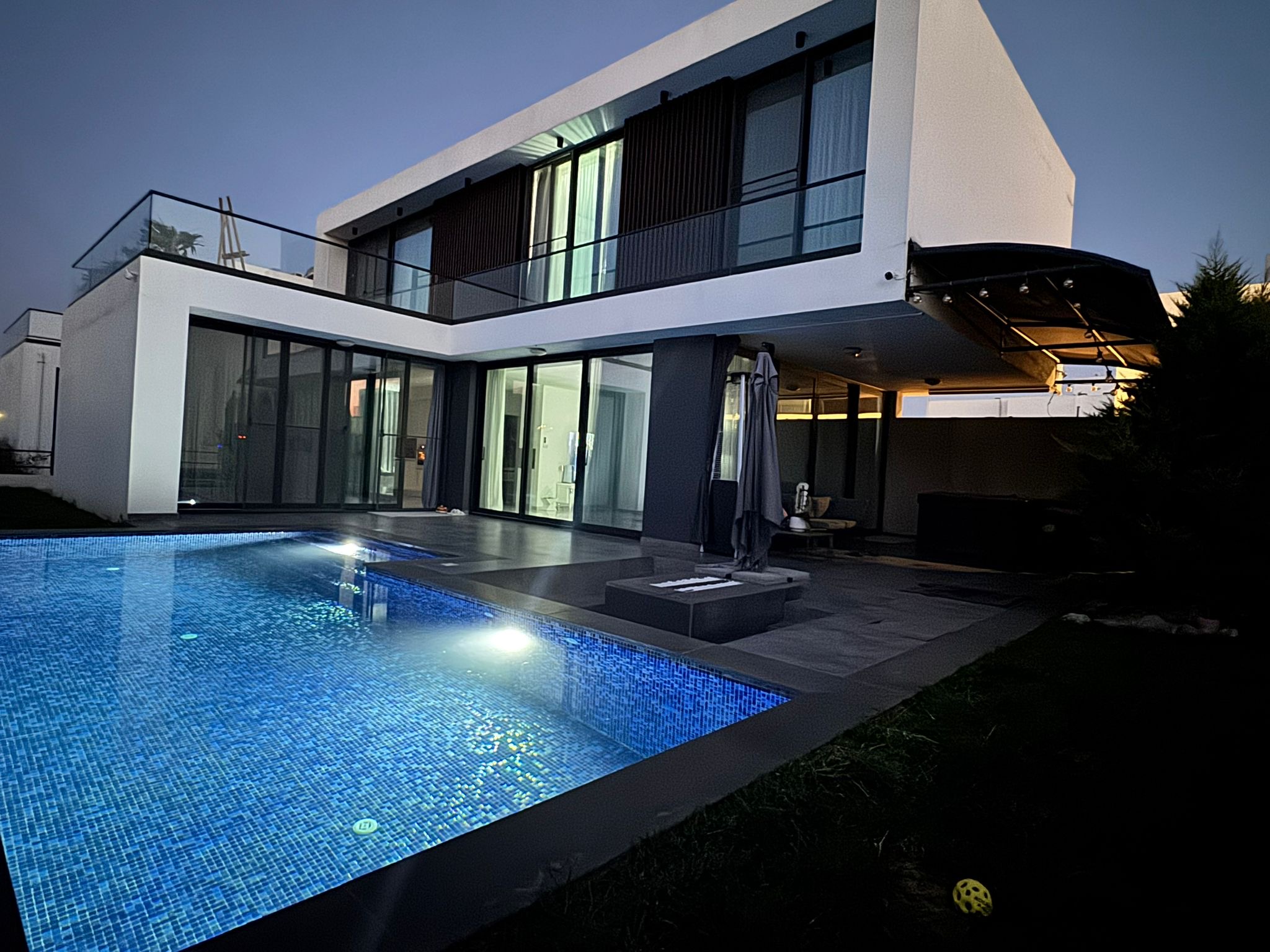 Villa facade and illuminated private pool at dusk